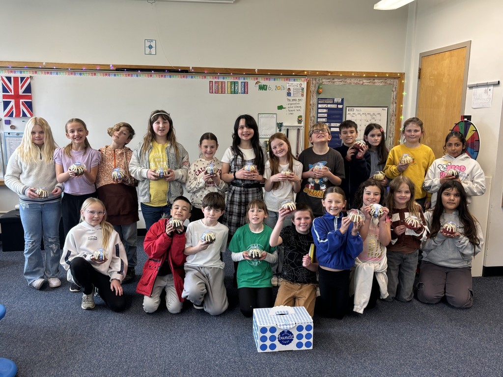 Students are standing with their bundt cakes in a classroom
