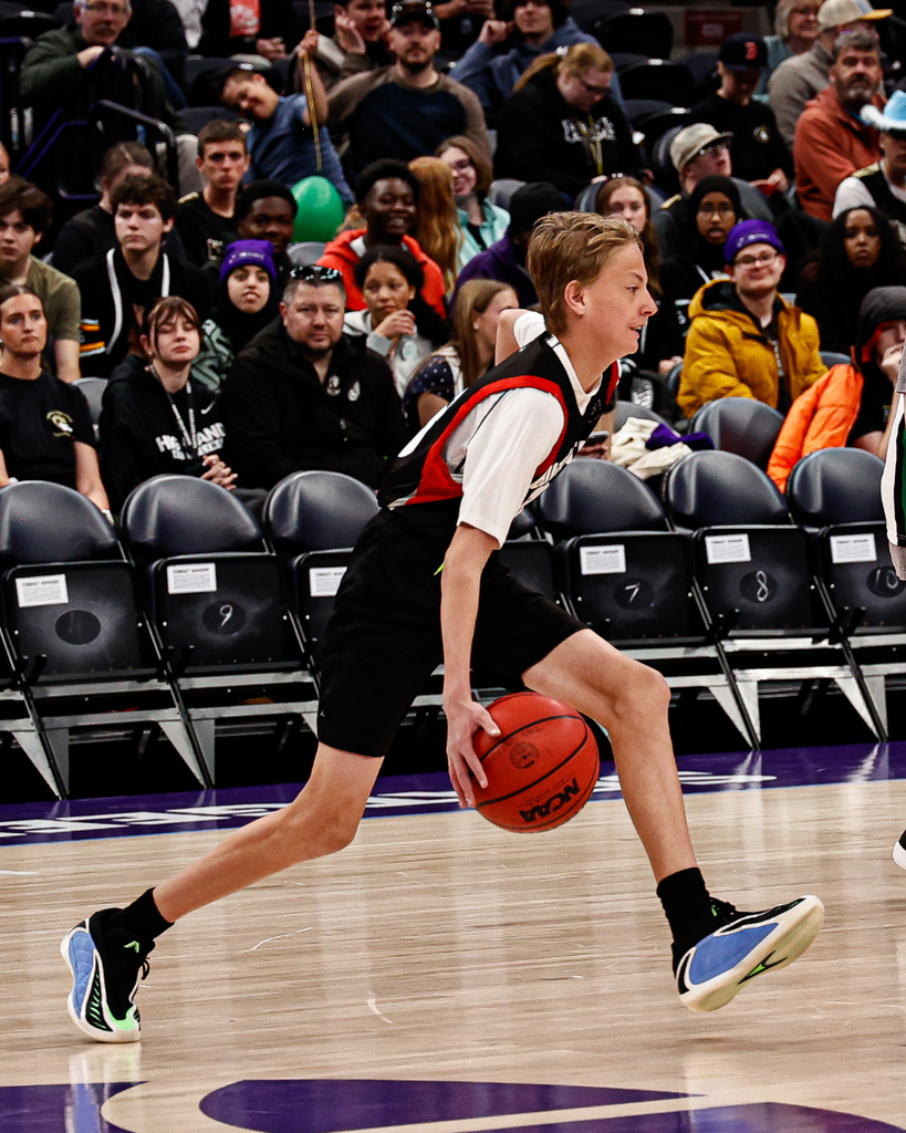 A student running with a basketball as he plays a game at the Delta Center. 