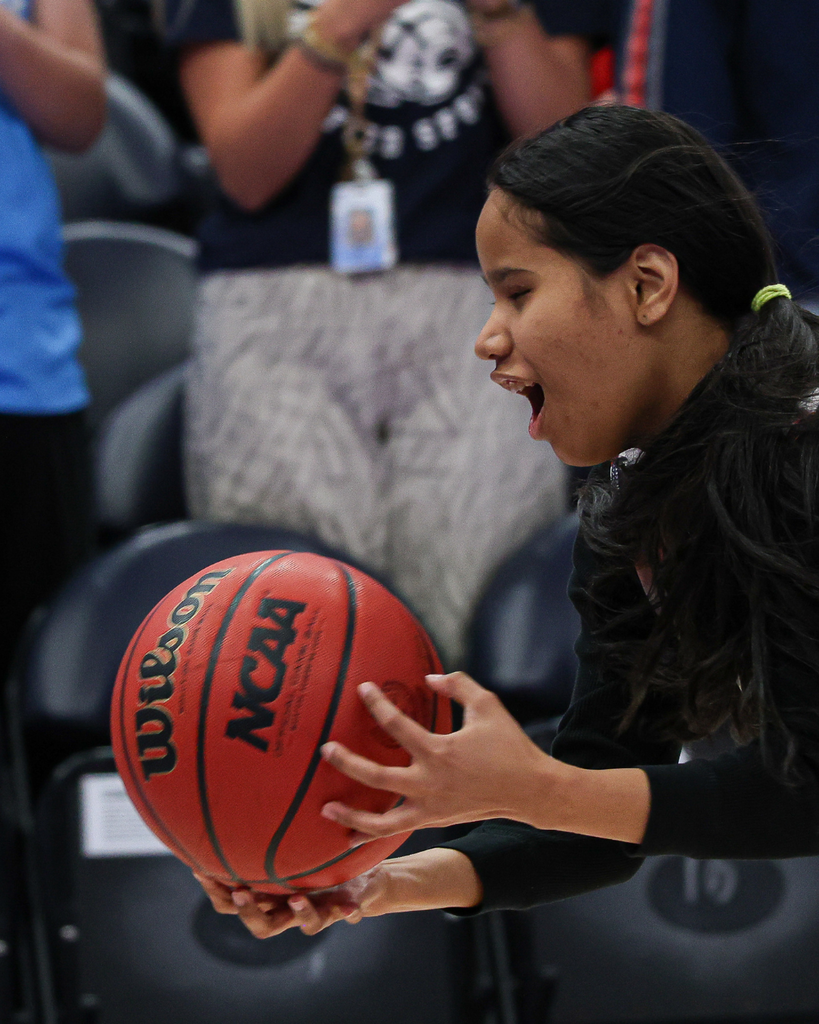 Student running with a basketball in her hand.
