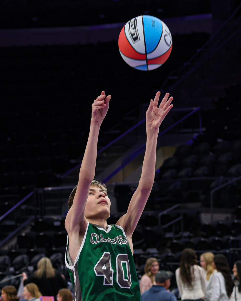 Student throwing a red, white and blue basketball.