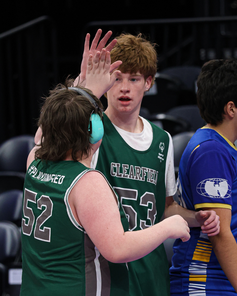 Two Clearfield High Unified Basketball teammates high five during a play.