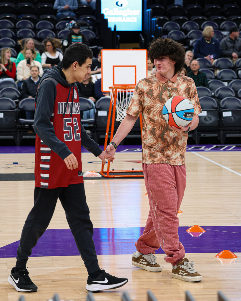 A student holds the hand of another student to guide him across the court during Unified State Basketball.