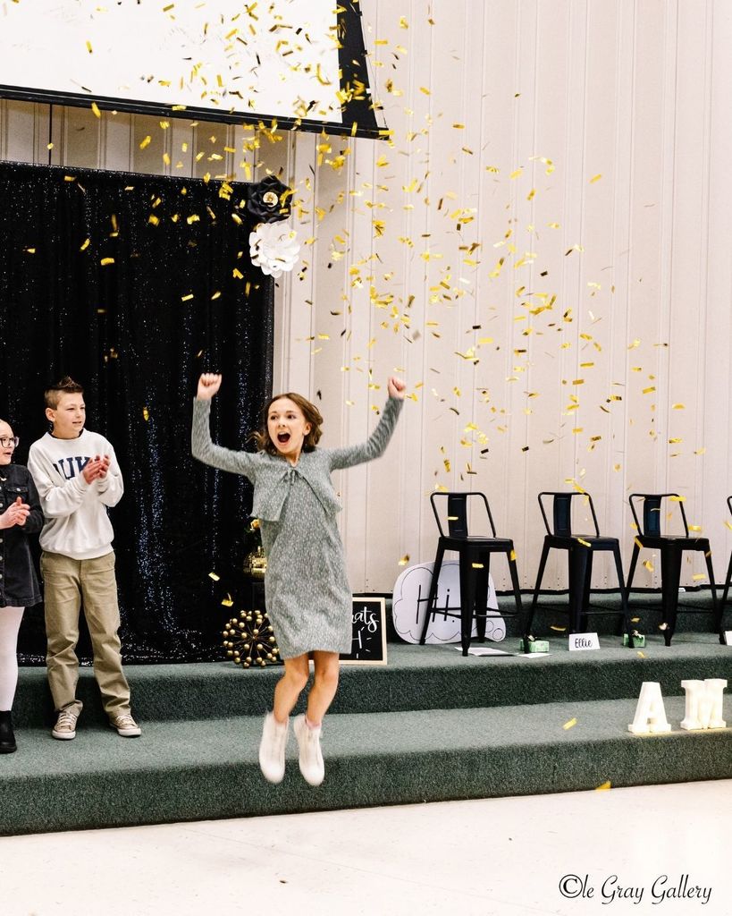 Student jumping with joy as confetti is falling from the sky.