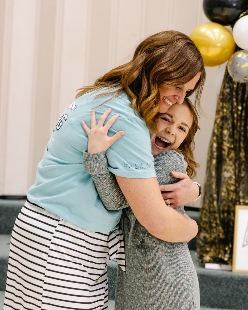 A student hugs her teacher. 
