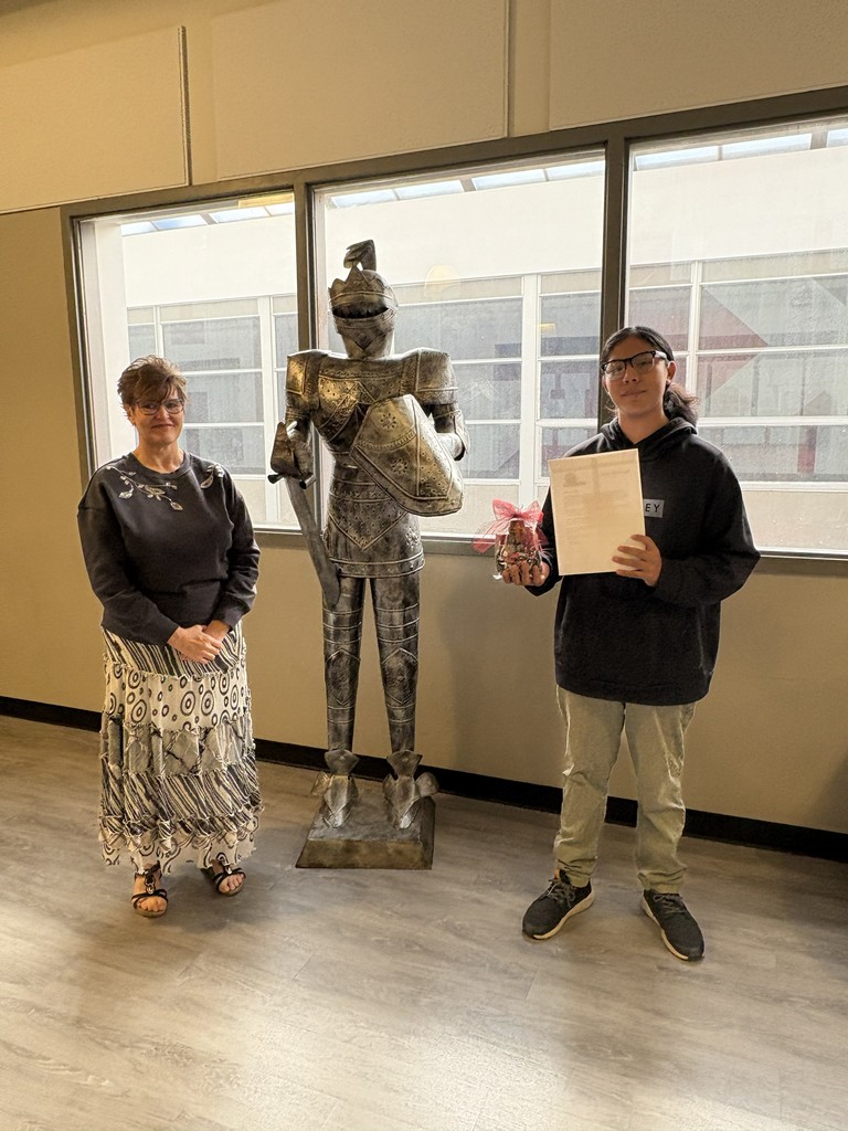 image of student and teacher standing next to a knight in armor statue