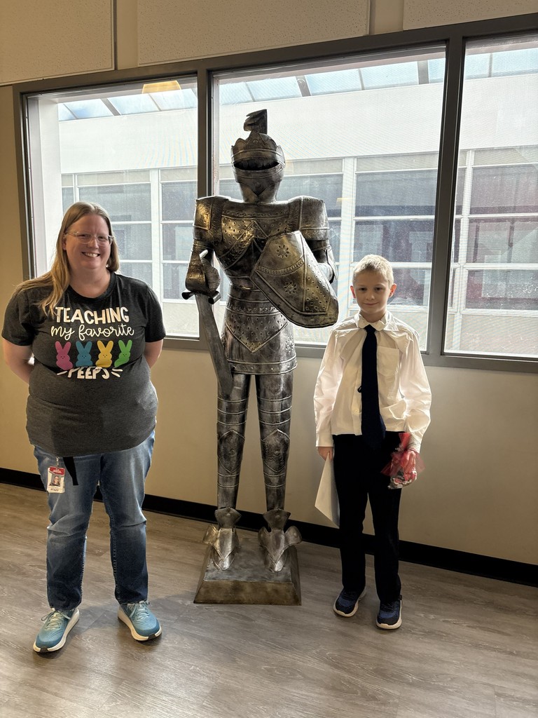 image of student and teacher standing next to a knight in armor statue
