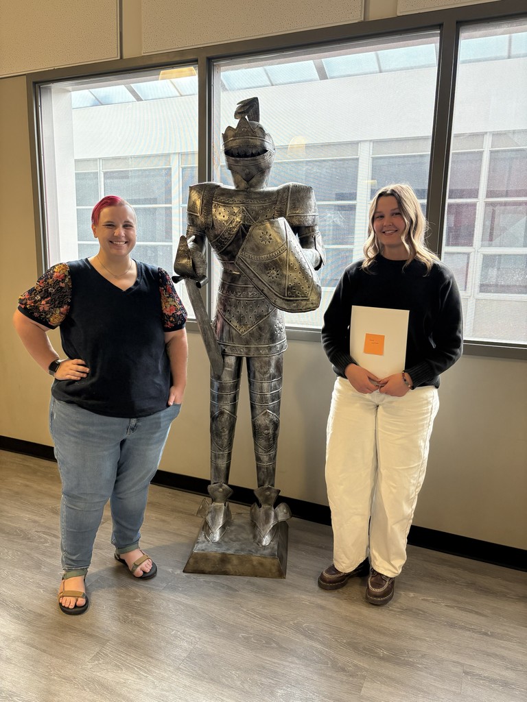 image of student and teacher standing next to a knight in armor statue