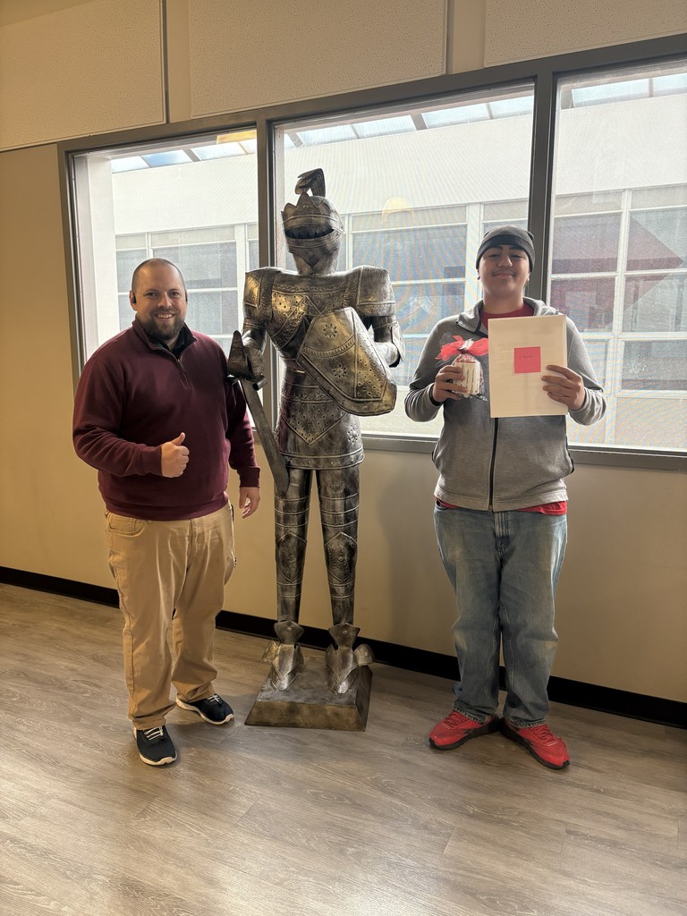 image of student and teacher standing next to a knight in armor statue