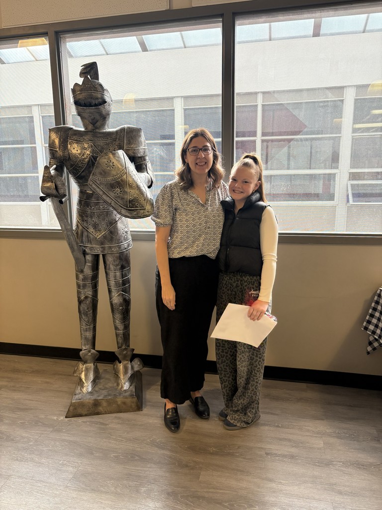 image of student and teacher standing next to a knight in armor statue