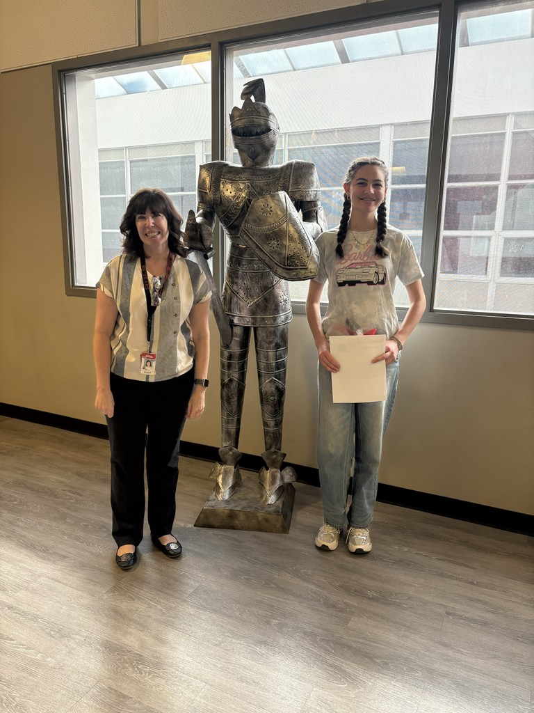 image of student and teacher standing next to a knight in armor statue