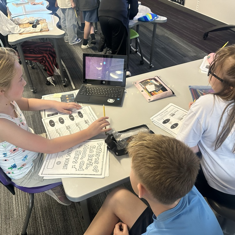 3 students around a laptop watching a video 