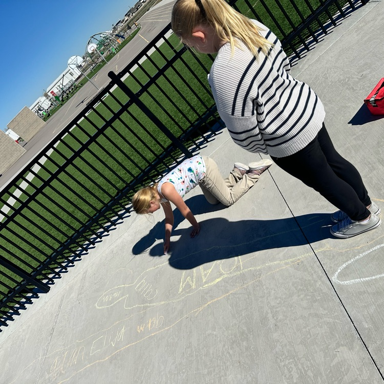 girl tracing another girls shadow on cement 
