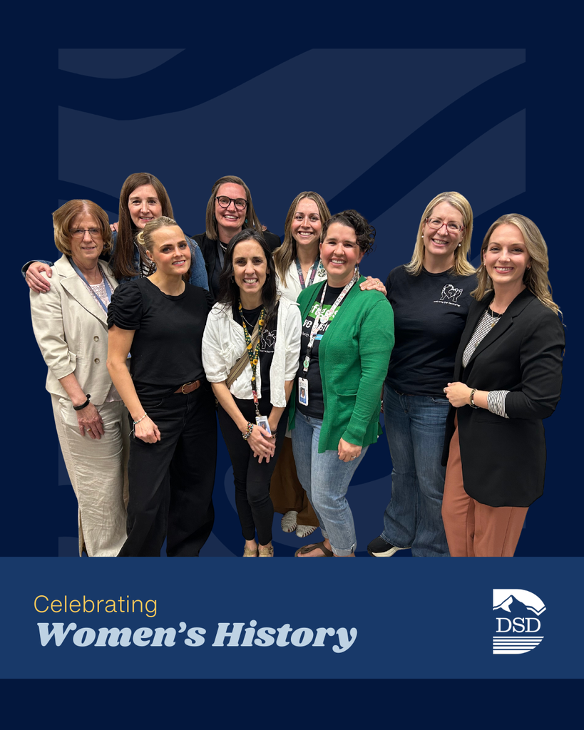A group of nine ladies posing in front of a blue wavy background. A banner that reads: "Celebrating Women's History"  with the Davis School District Logo.