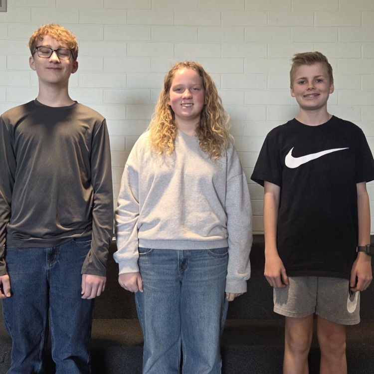 two boys and a girl stand an smile in the hallway! 