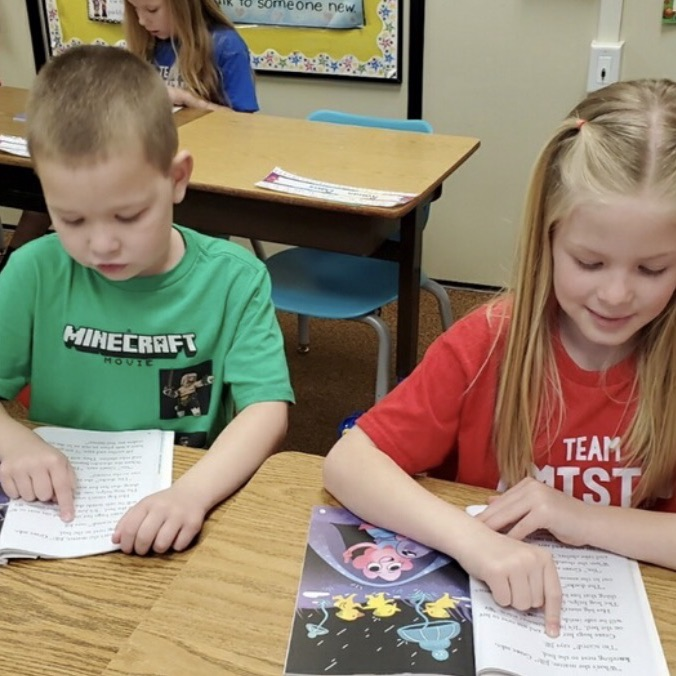 1st graders reading together with a partner to practice their skills