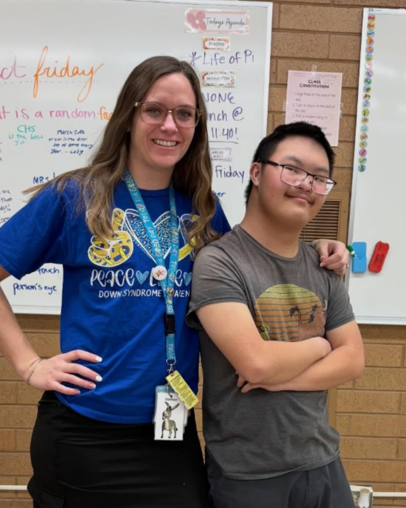 A teacher and student posing with their mismatched socks.