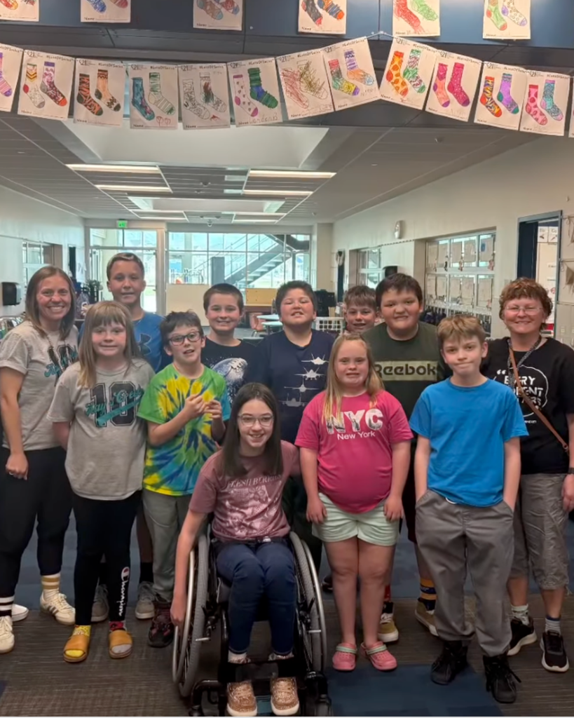 A group of students smiling while wearing their mismatched socks.