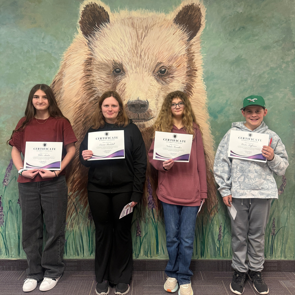 Students standing in front of wall holding certificates