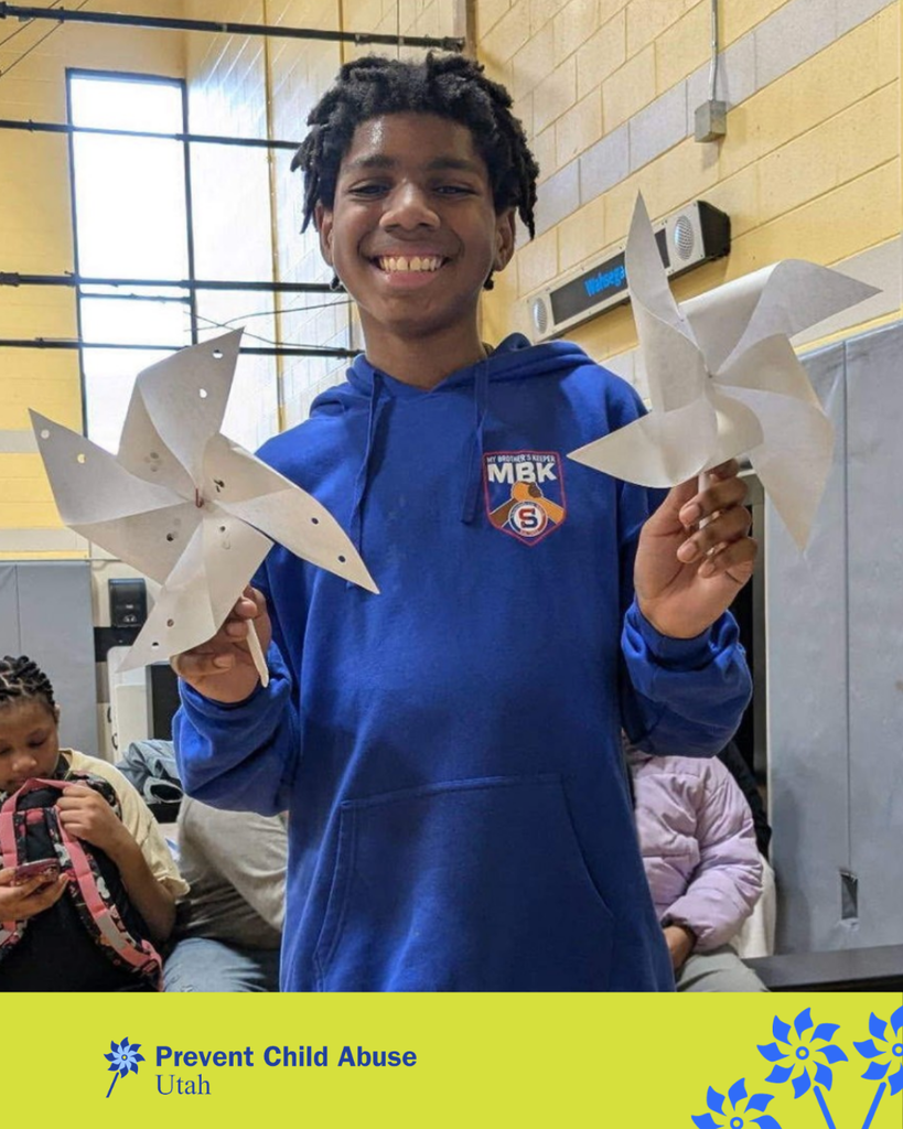 A student wearing blue holding pinwheels. The bottom  says: "Prevent Child Abuse Utah"