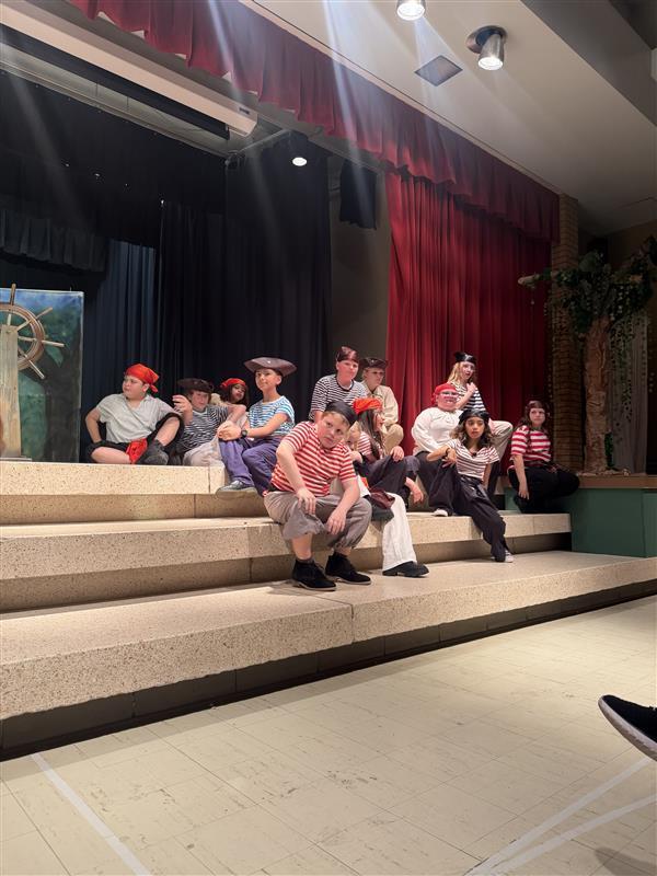 Peter Pan Pirates sitting on the stage while listening to Captian Hook