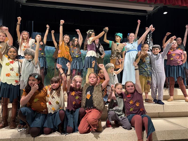 Peter Pan Jr. Cast during a performance of Ugh-a-wug on the stage with arms raised in the air