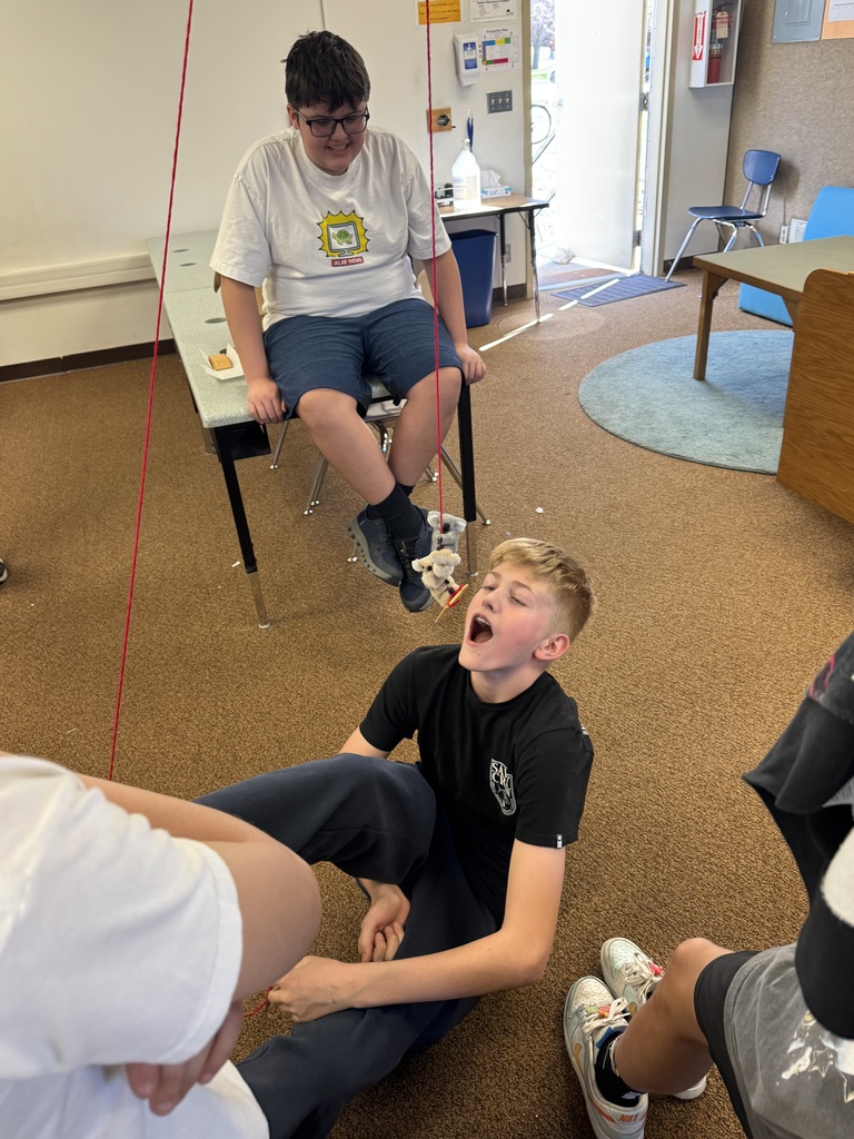 A photo of kids doing a STEM activity with string tied around their ankles