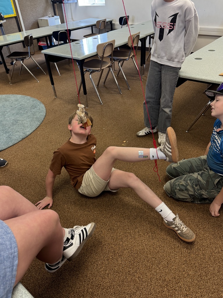 A photo of kids doing a STEM activity with string tied around their ankles