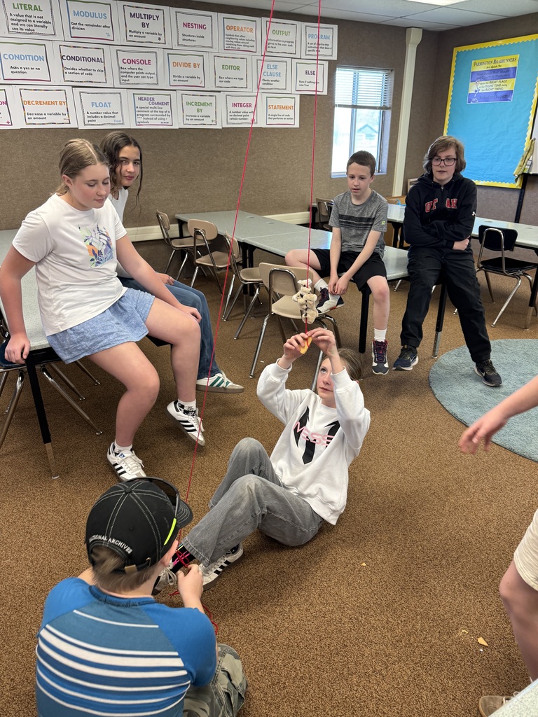 A photo of kids doing a STEM activity with string tied around their ankles