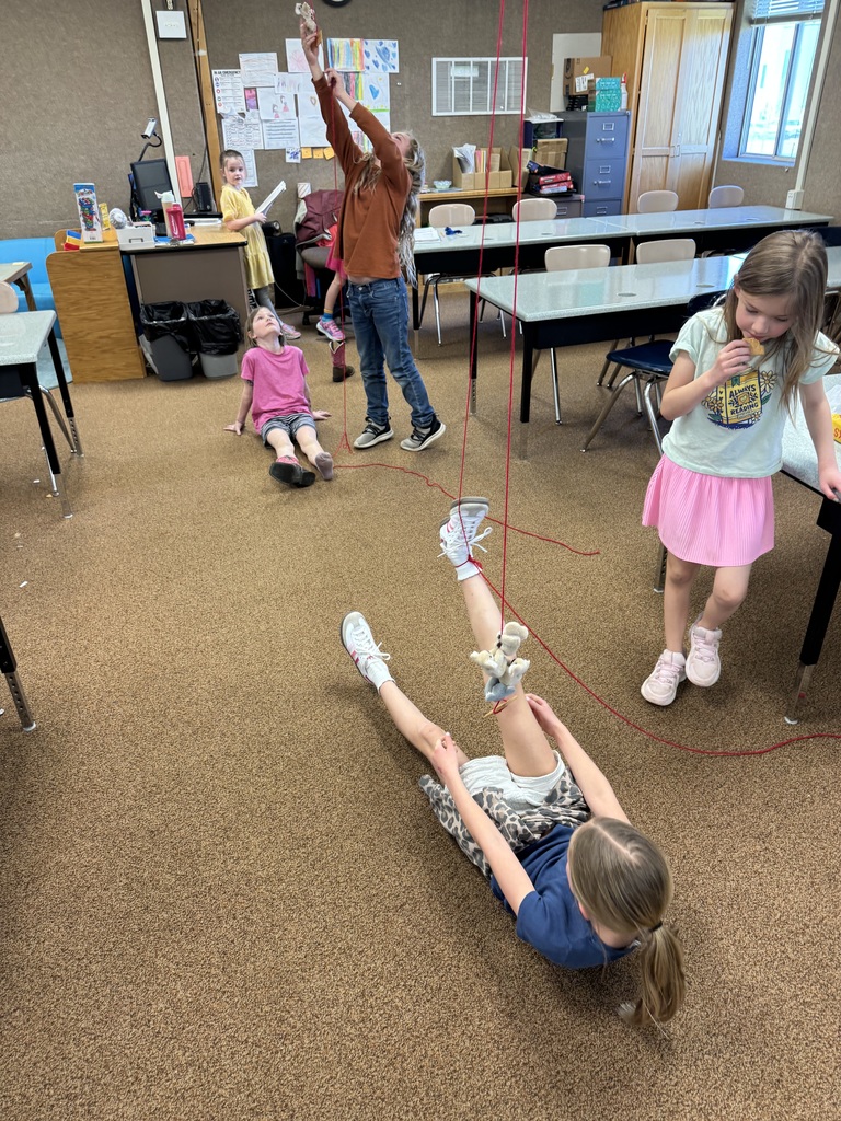 A photo of kids doing a STEM activity with string tied around their ankles