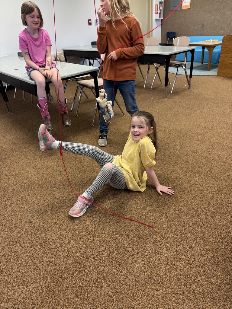 A photo of kids doing a STEM activity with string tied around their ankles