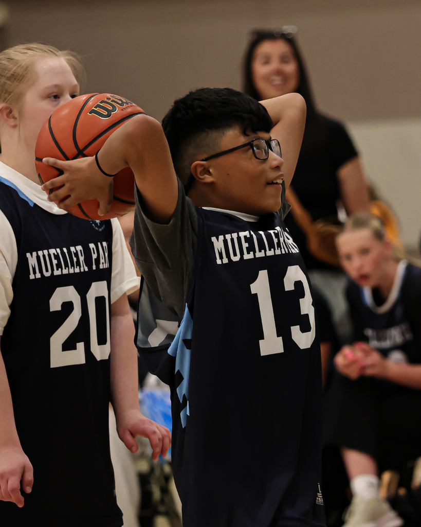 A Mueller Park student wearing a Mueller Park #13 jersey getting ready to throw a basketball.