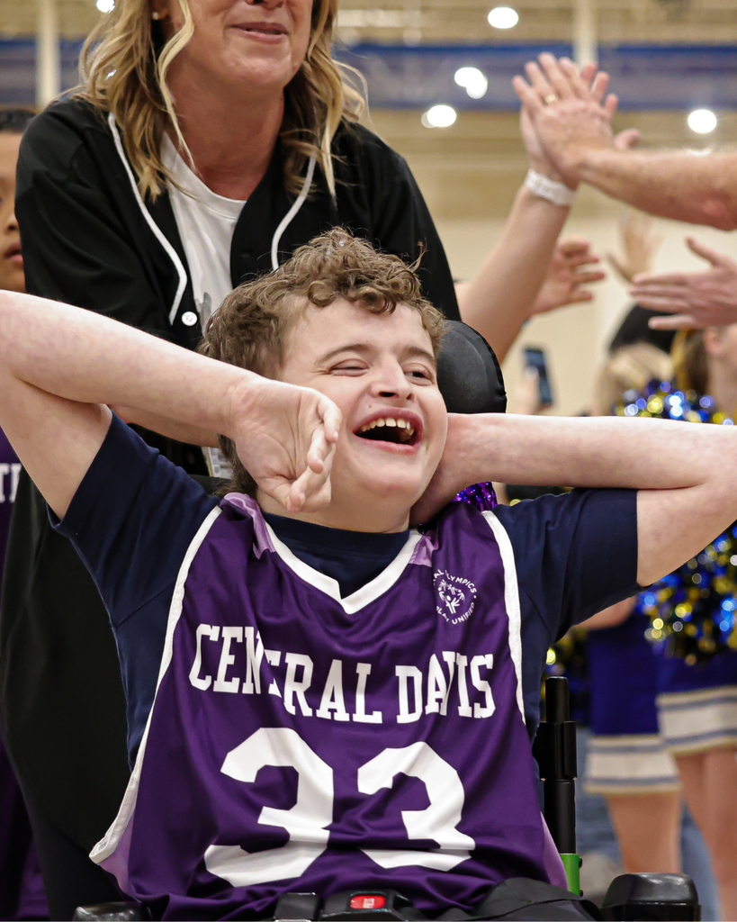 A student in a Central Davis #33 jersey smiles with his arms around his face. 