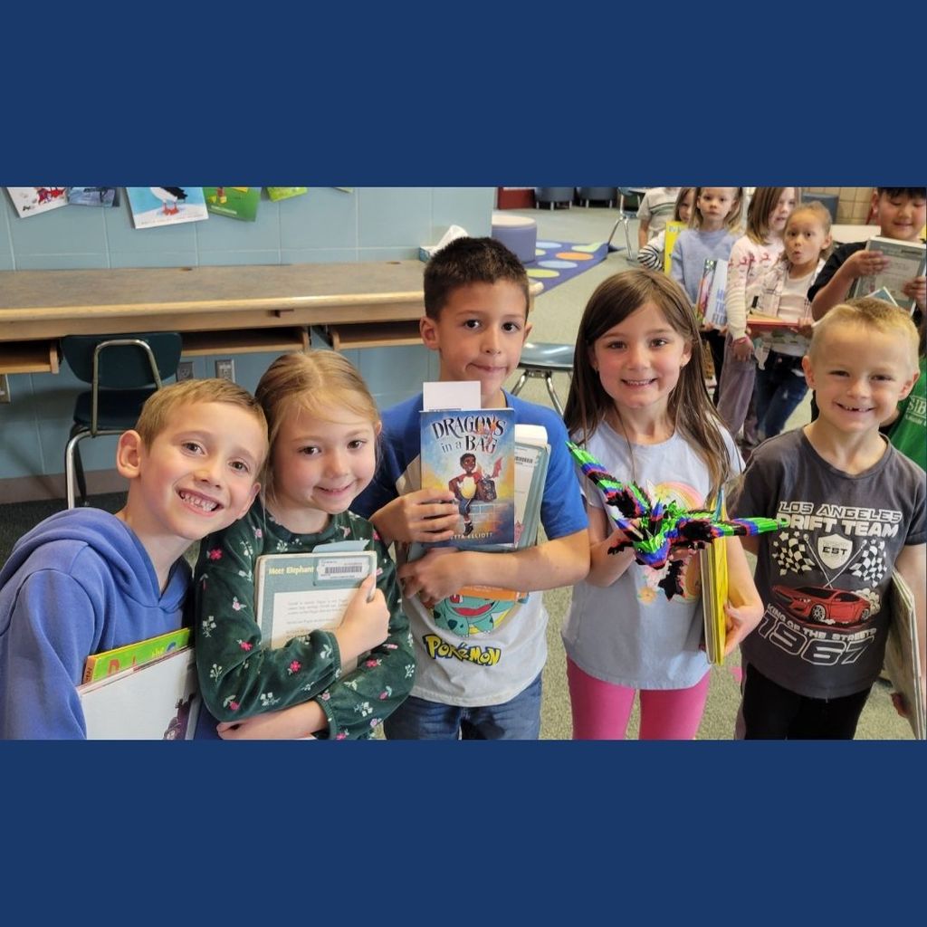 Students holding the book "Dragons in a Bag" and a 3d printed dragon.