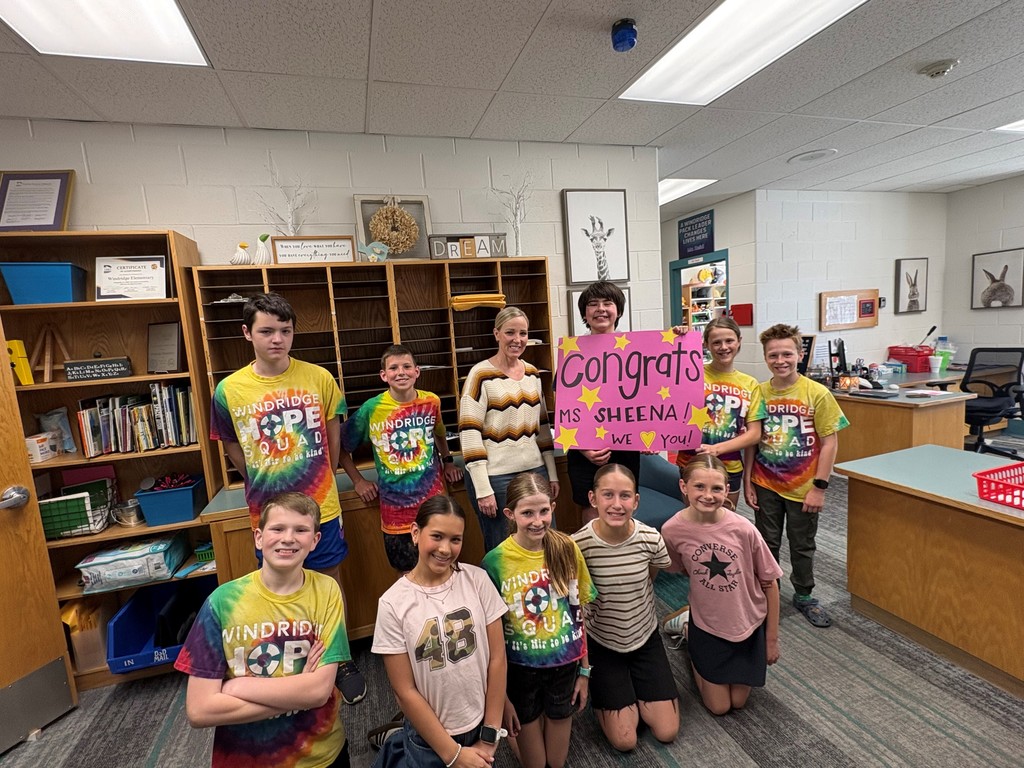 Group of kids posing with a school staff member holding a sign that says Congrats Ms. Sheena, we love you!