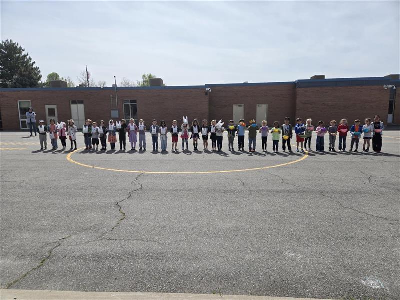 a line of 33 students holding their handcrafted easter baskets, about to go on an egg hunt