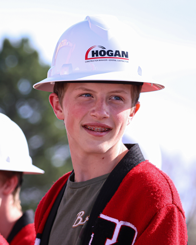 A Kaysville Junior High student wearing a construction hat smiles Kaysville Field House Groundbreaking.