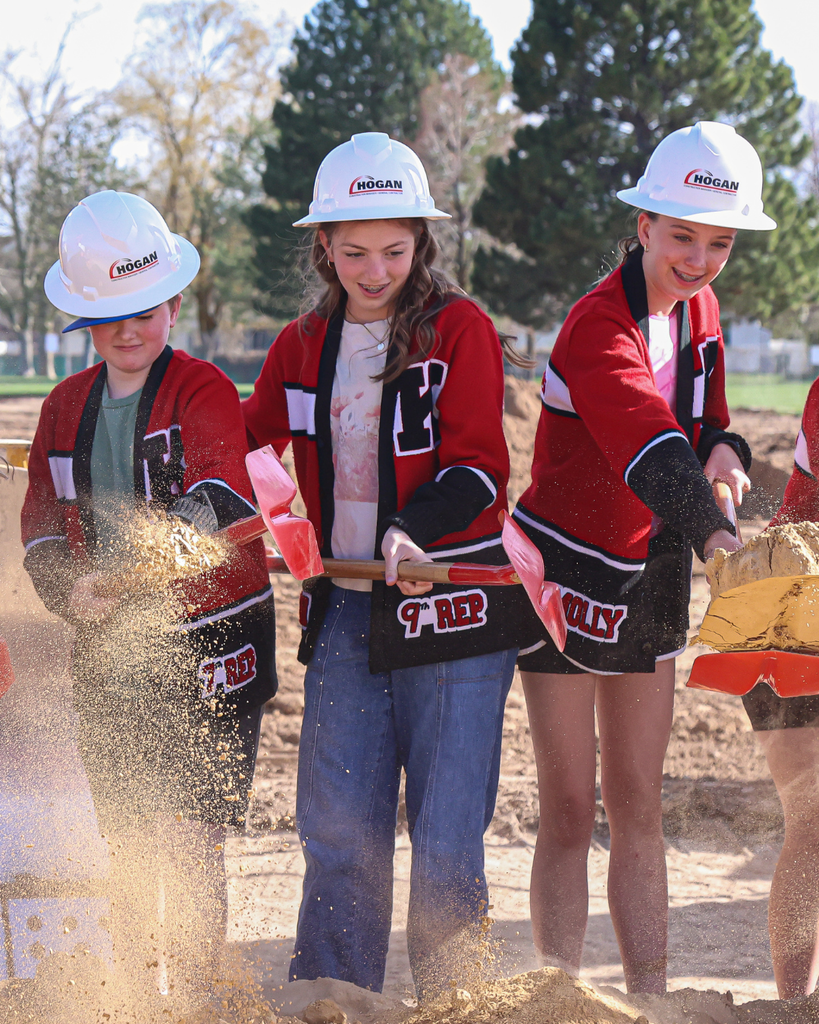 Group of students holding shovels and wearing hard hats groundbreaking. 