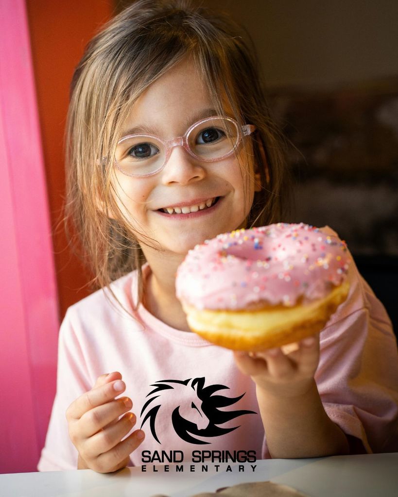 Photo of a little girl and a pink frosted donut. Sand Springs Elementary Stallion logo