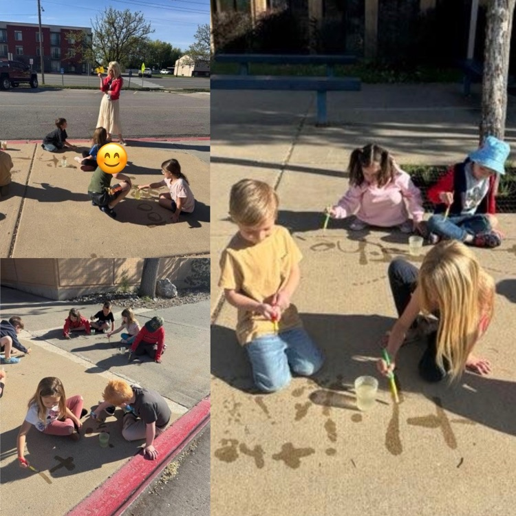 kindergartners practicing writing tricky sight words outside using water and brushes on the sidewalk