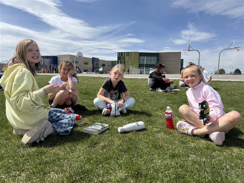 group of girls on the grass with drinks and books