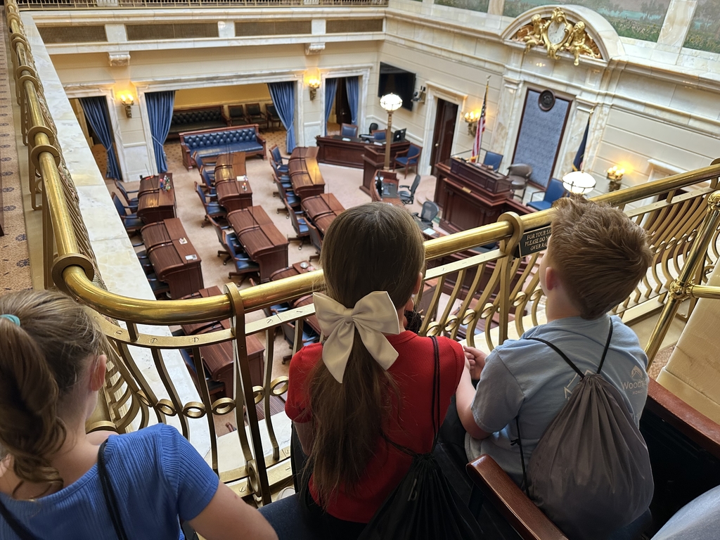 3 students looking down into a room with desks
