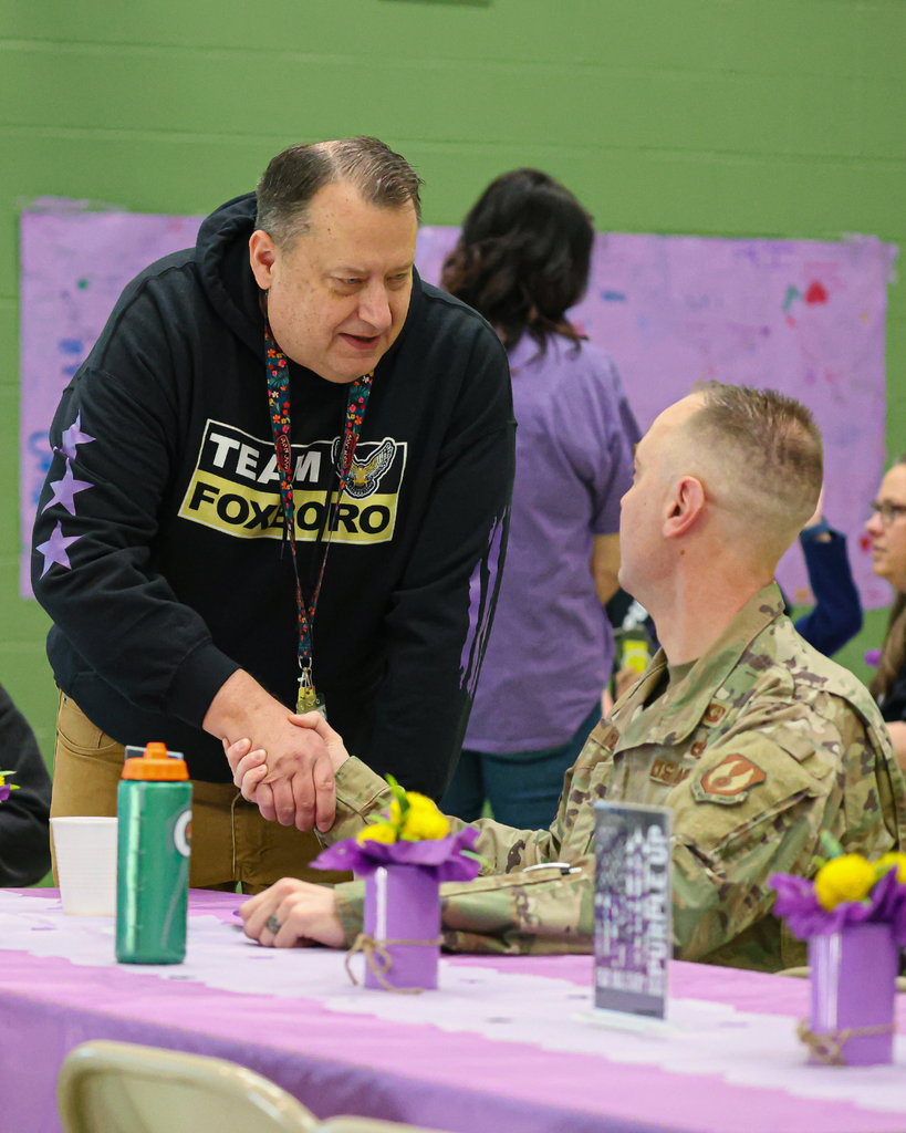 Assistant principal shakes the hand of a military parent.