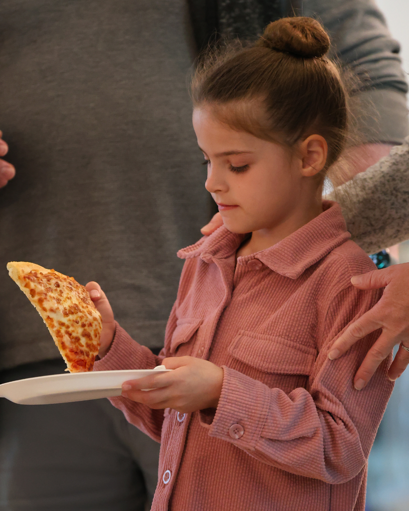 A student picking up a slice of pizza.