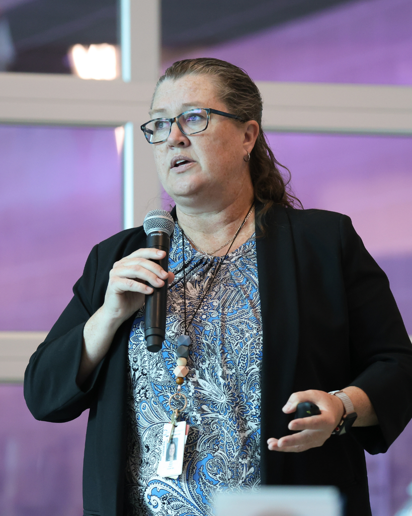 An instructor speaking into the microphone while giving a presentation.