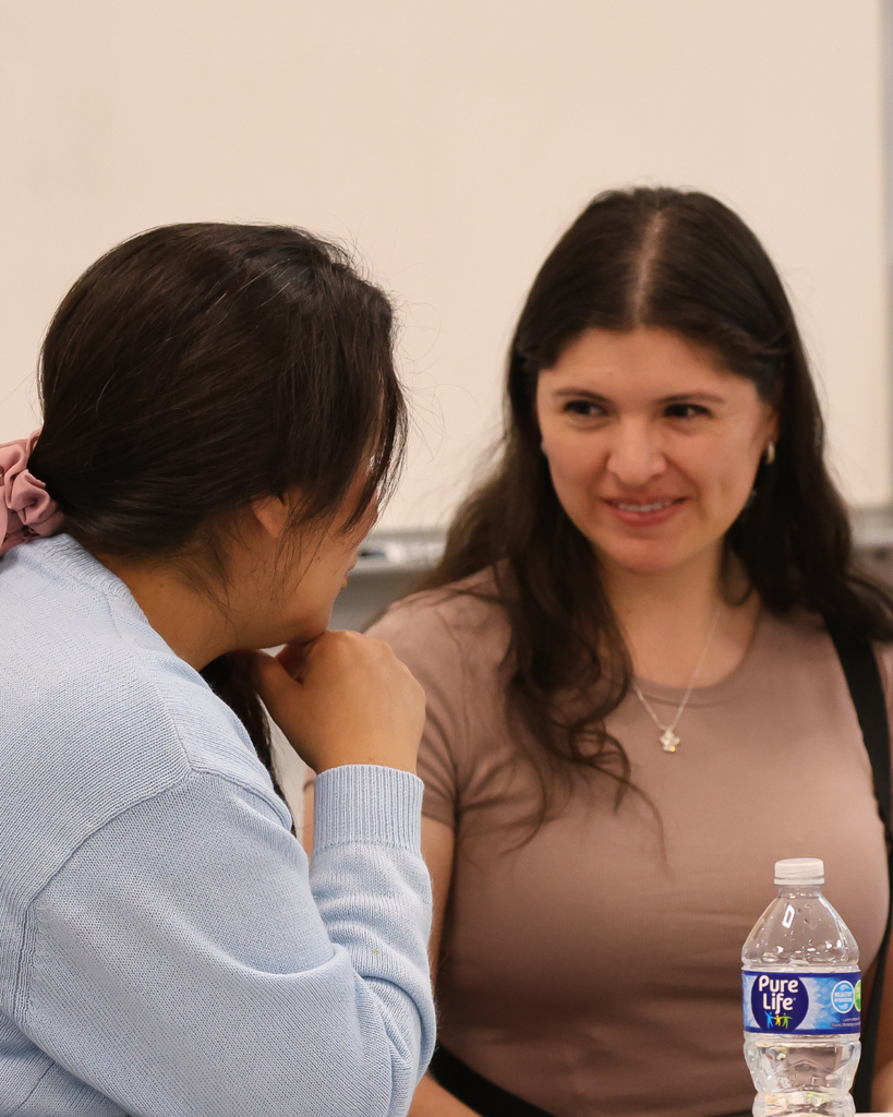 Two adults sitting in a classroom smiling.