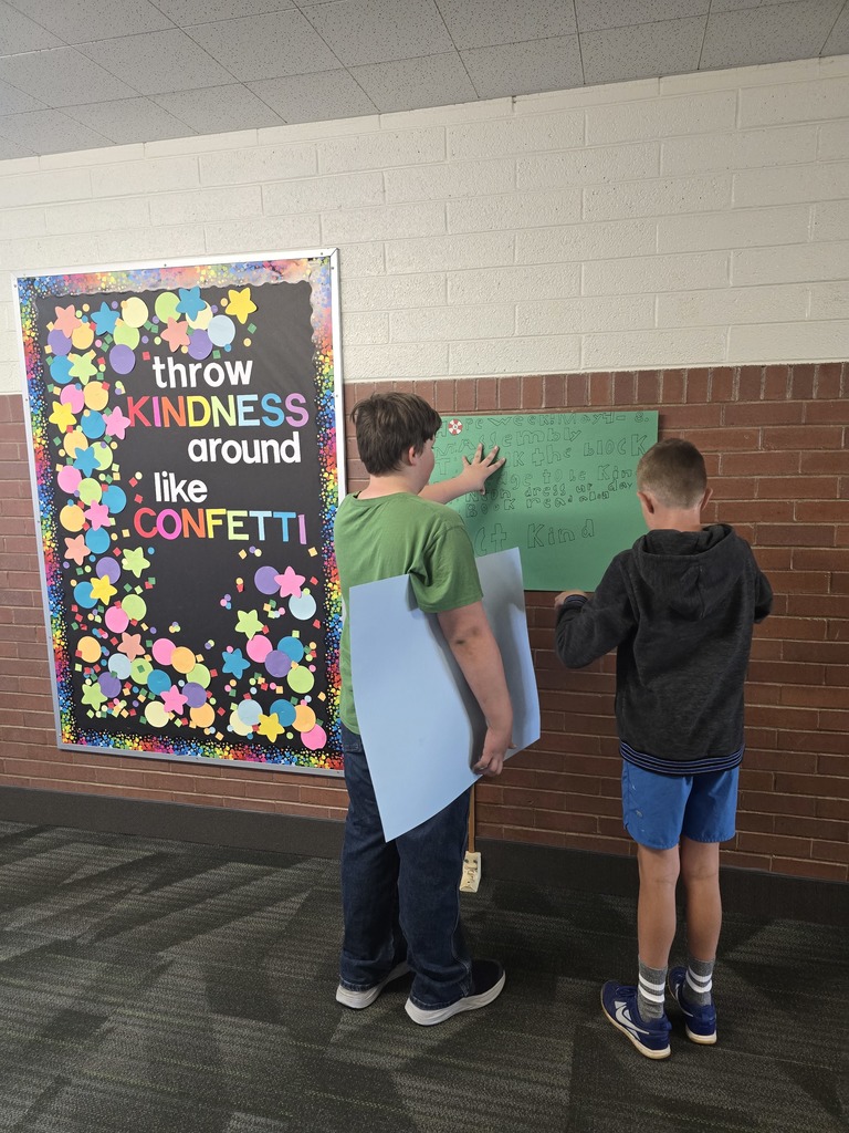 two students hanging a poster at the school