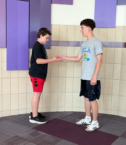 Students in the hallway having fun with a special handshake