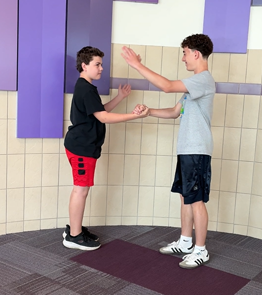Students in the hallway having fun with a special handshake