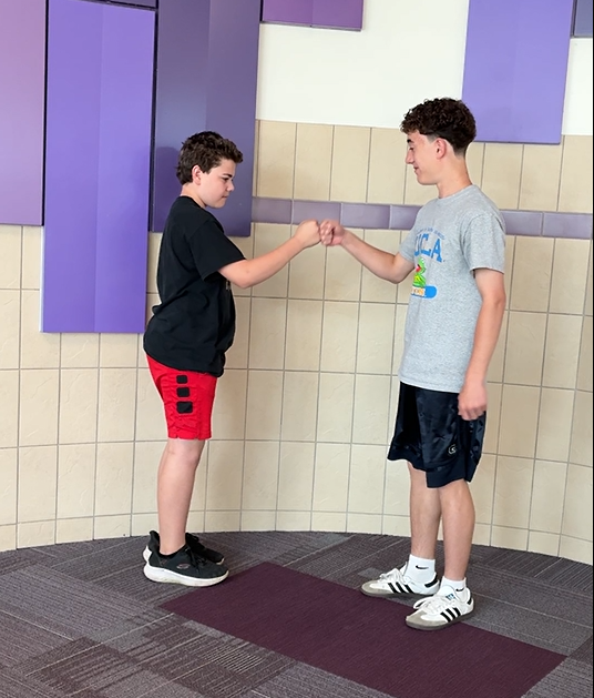 Students in the hallway having fun with a special handshake