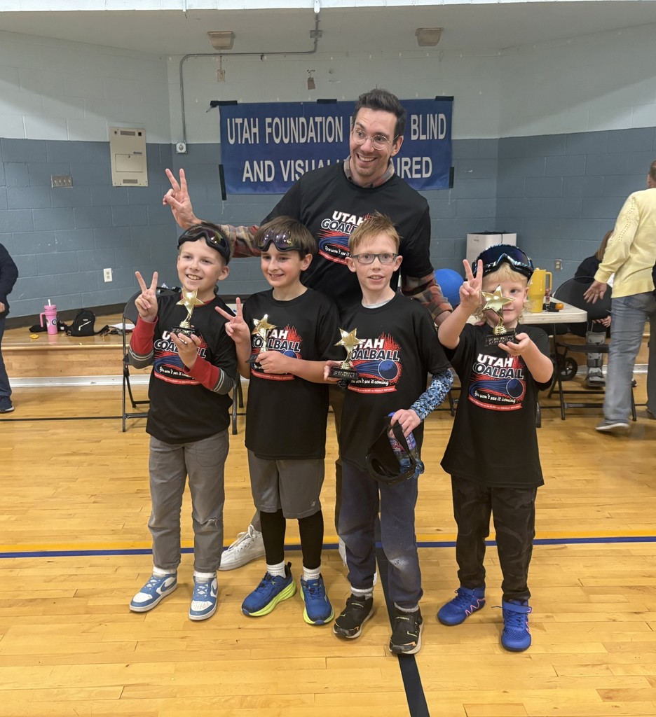 A goal ball team consisting of 4 students and their coach with their second place trophies